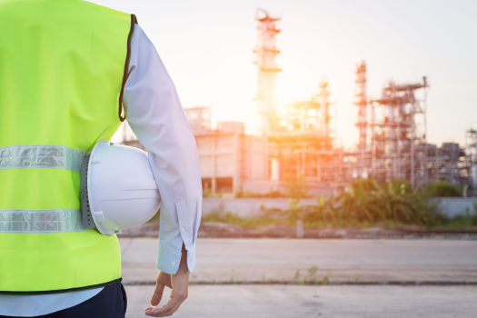 Man with hard hat looking at oil refinery